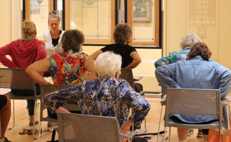elderly people doing yoga exercises in chairs