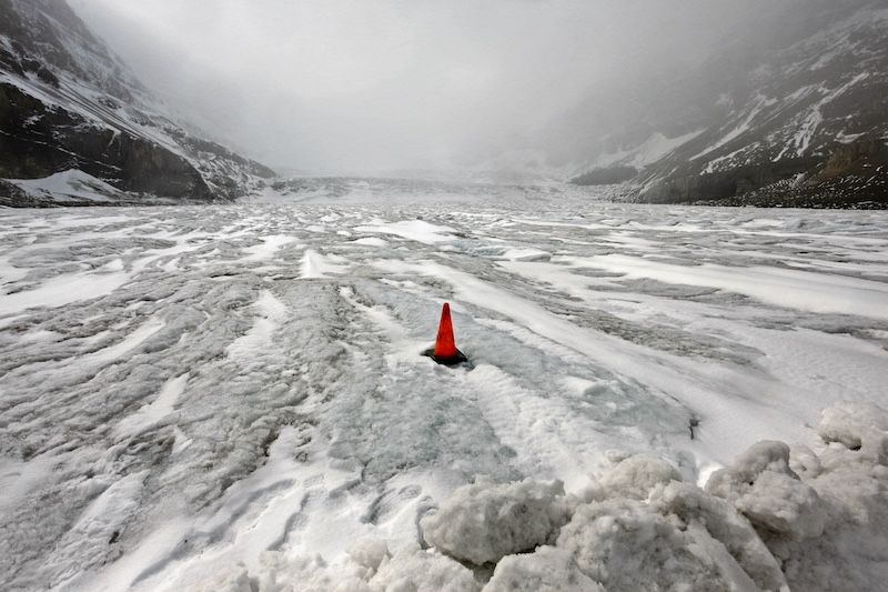 Robert von Sternberg's photograph "Columbia, Icefield" depicts a neon orange traffic cone in the center of an icy, sludgy landscape.