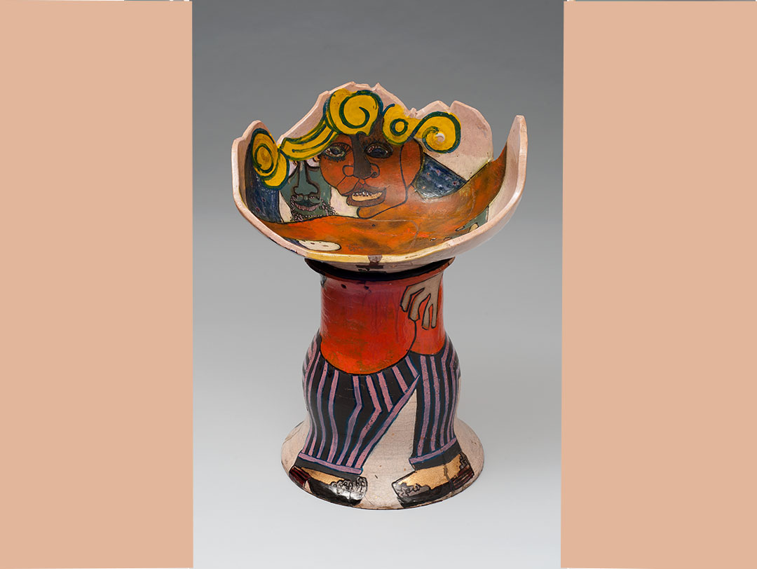 Camille Billops' Raku clay piece "El Pimpo's Chair," a stool with a half-sphere-shaped seat and a single large foot. The seat shows a topless Black woman, spreading out her arms. Behind her, embracing her, is a green-faced man, perhaps the pimp of the title. The painting/glazing continues on the rest of the stool, with the woman's legs and high-heel-shod feet pictured on the base and the man's purple-and-black-striped pants and his shoes.