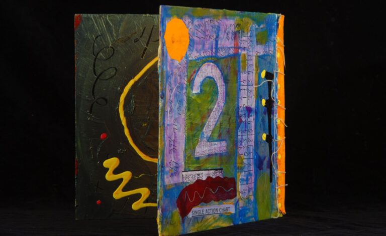 A detail of a collaged artist's book by Joyce Wellman, featuring the number 2 in purple on the back