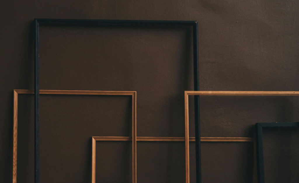 a stock photo of empty frames leaning against a brown wall
