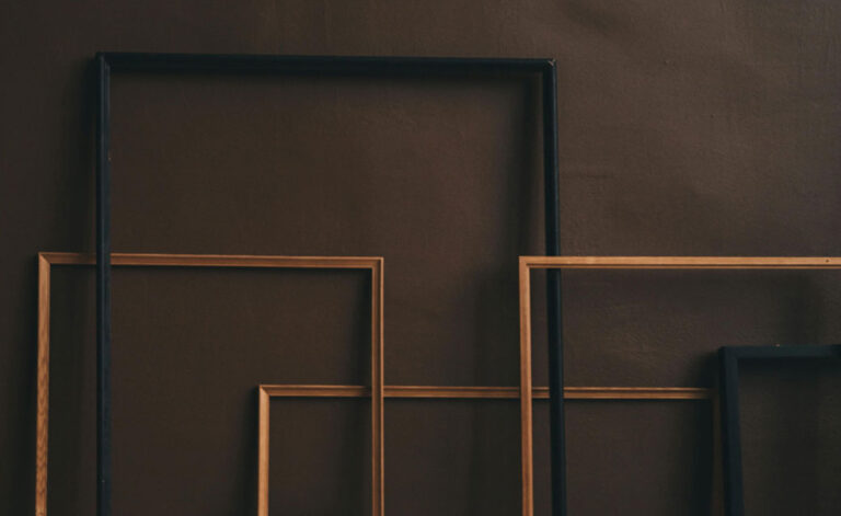 a stock photo of empty frames leaning against a brown wall