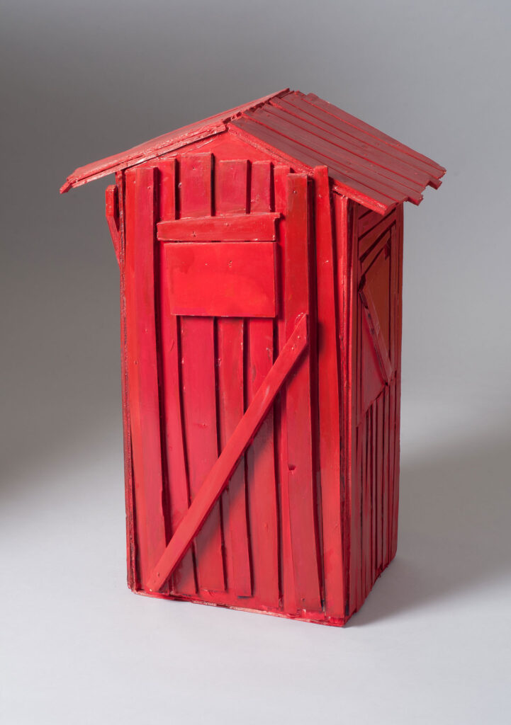 A small sculpture of a rustic shack, painted bright red