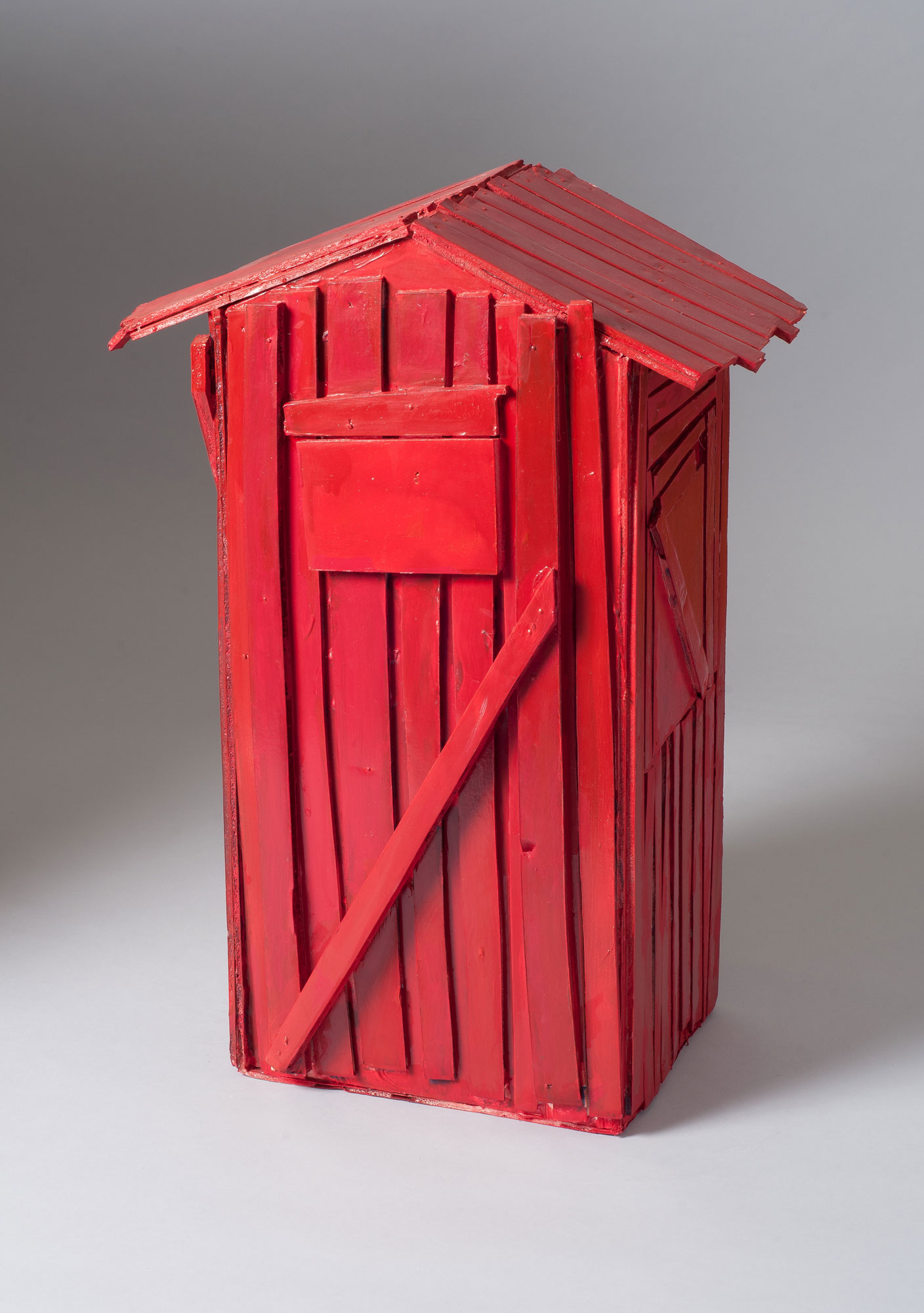 A small sculpture of a rustic shack, painted bright red