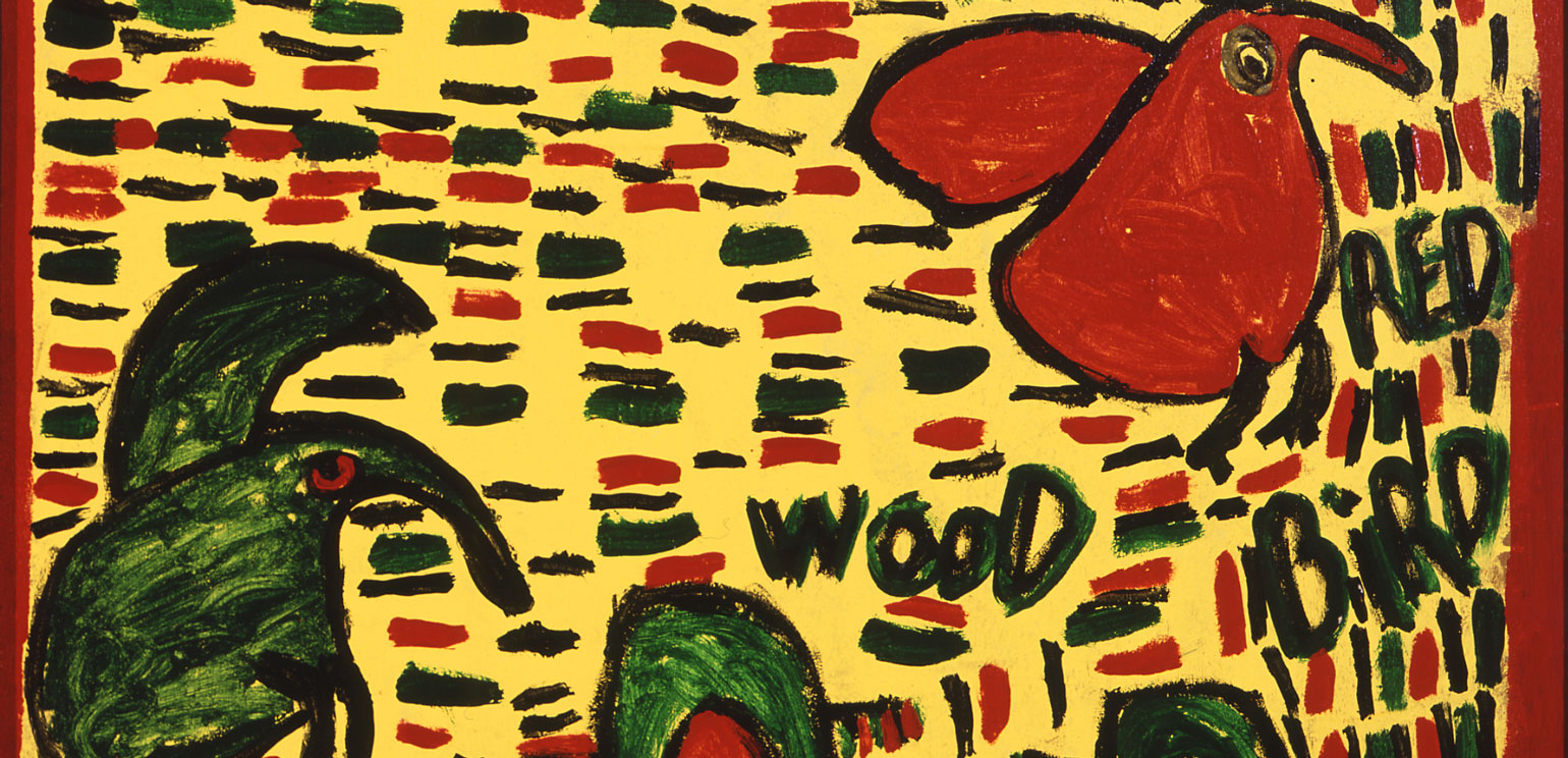A detail of a brightly colored painting by Willie Jinks on a large vertical piece of wood (possibly a door). It has a bright yellow background and green, red and black paint that creates dogs, a tree and some words.