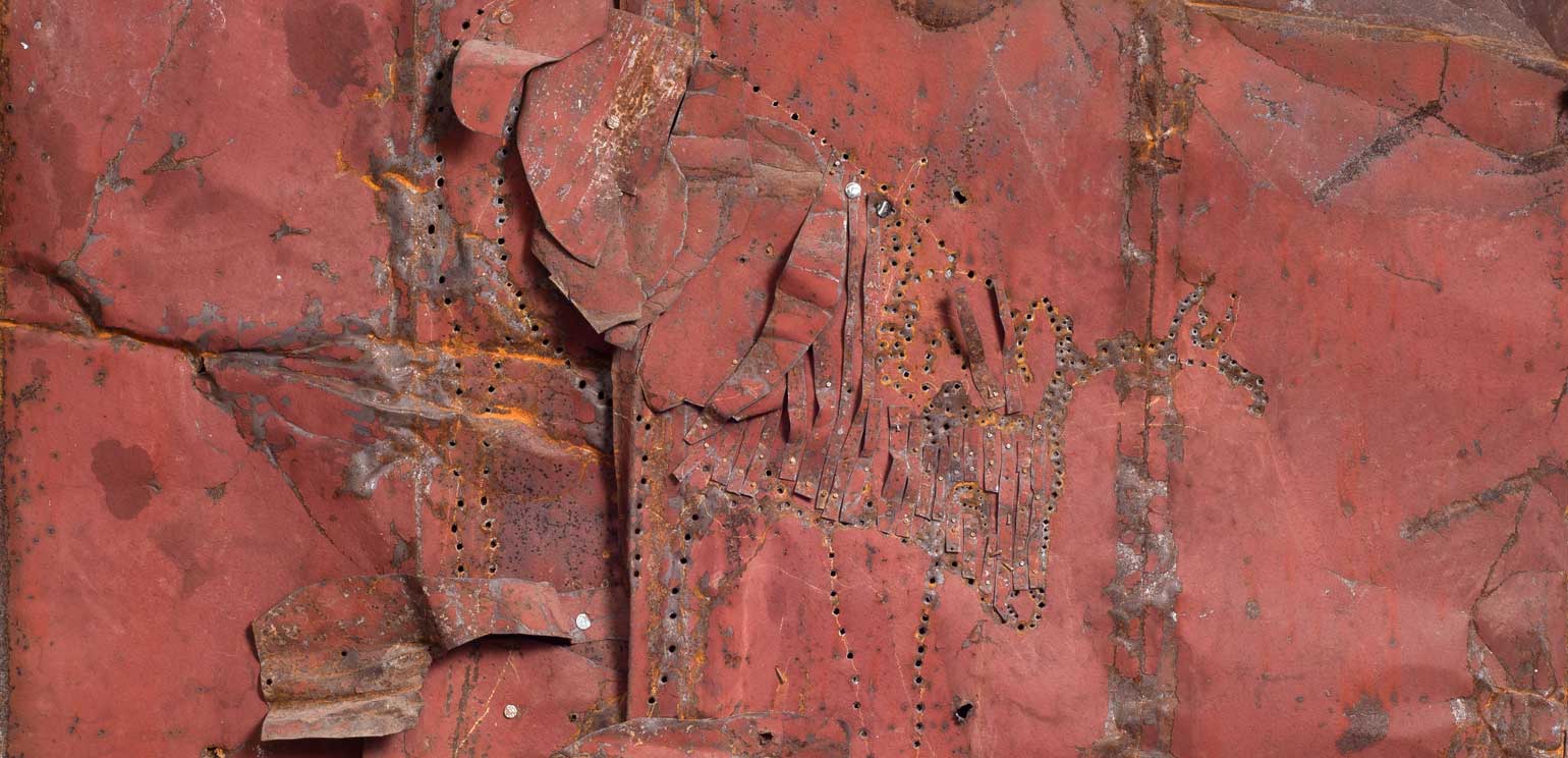 A detail of Ronald Lockett's “Undiscovered,” a work in red, rusted tin and colored pencil mounted on wood.