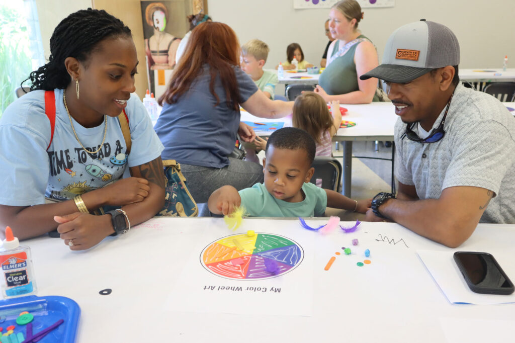 A family at Toddler Tuesday, doing a color wheel activity in the studio classroom