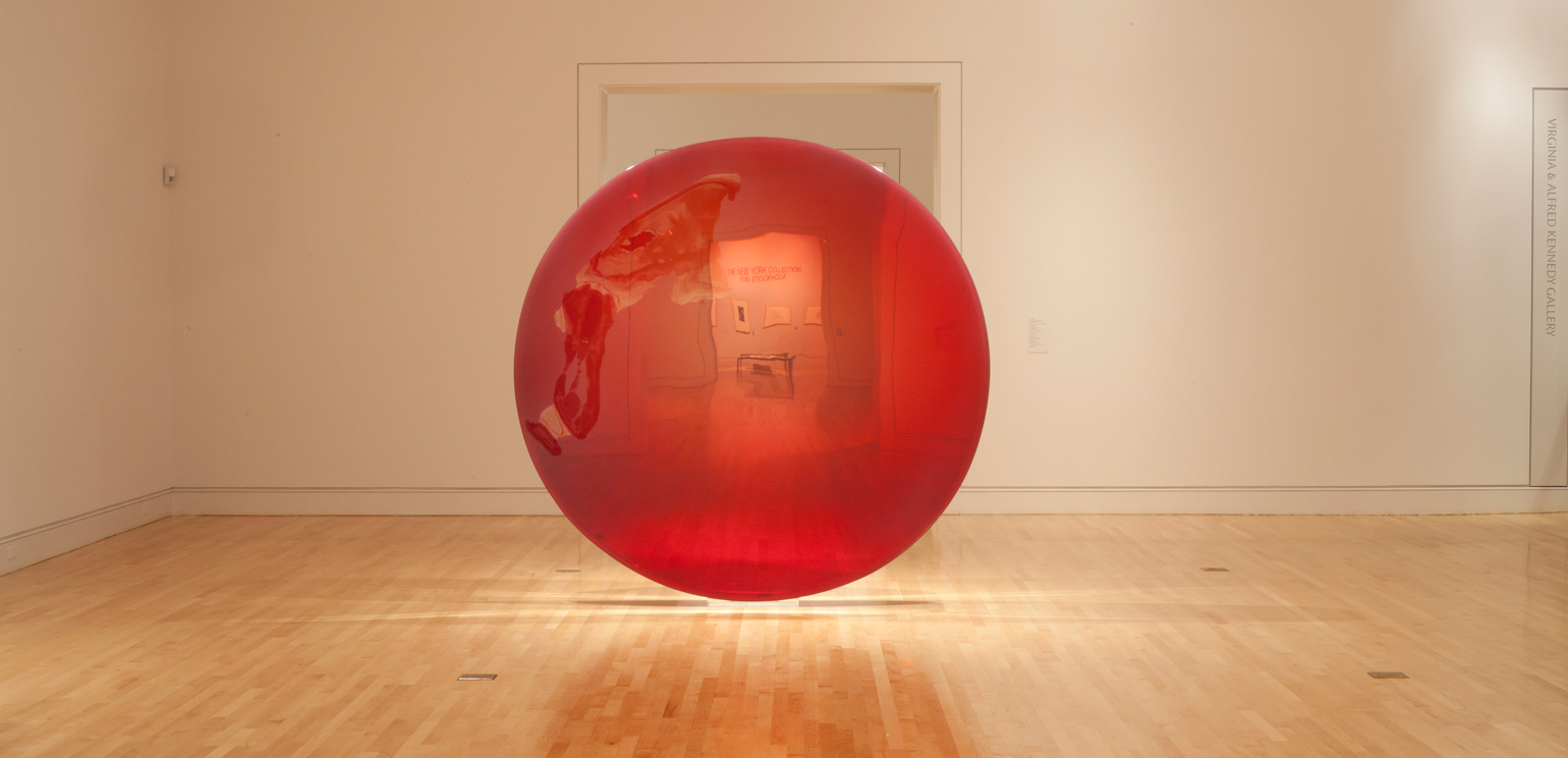 A color photograph of a large, circular, red sculpture by light and space artist DeWain Valentine, installed at the museum