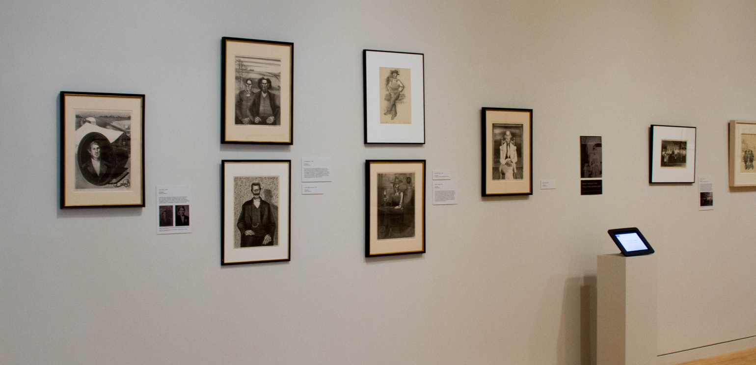 An installation photograph of the exhibition "The Lithographs of Carroll Cloar" at the Georgia Museum of Art, showing lithographs framed and hung in a gallery
