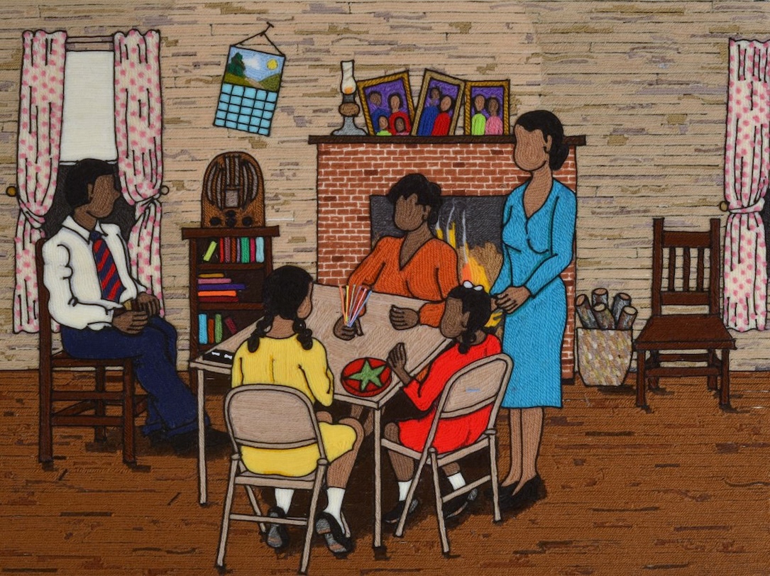 A family sits at a table in front of a fireplace to play Pick-up Sticks and Chinese checkers.