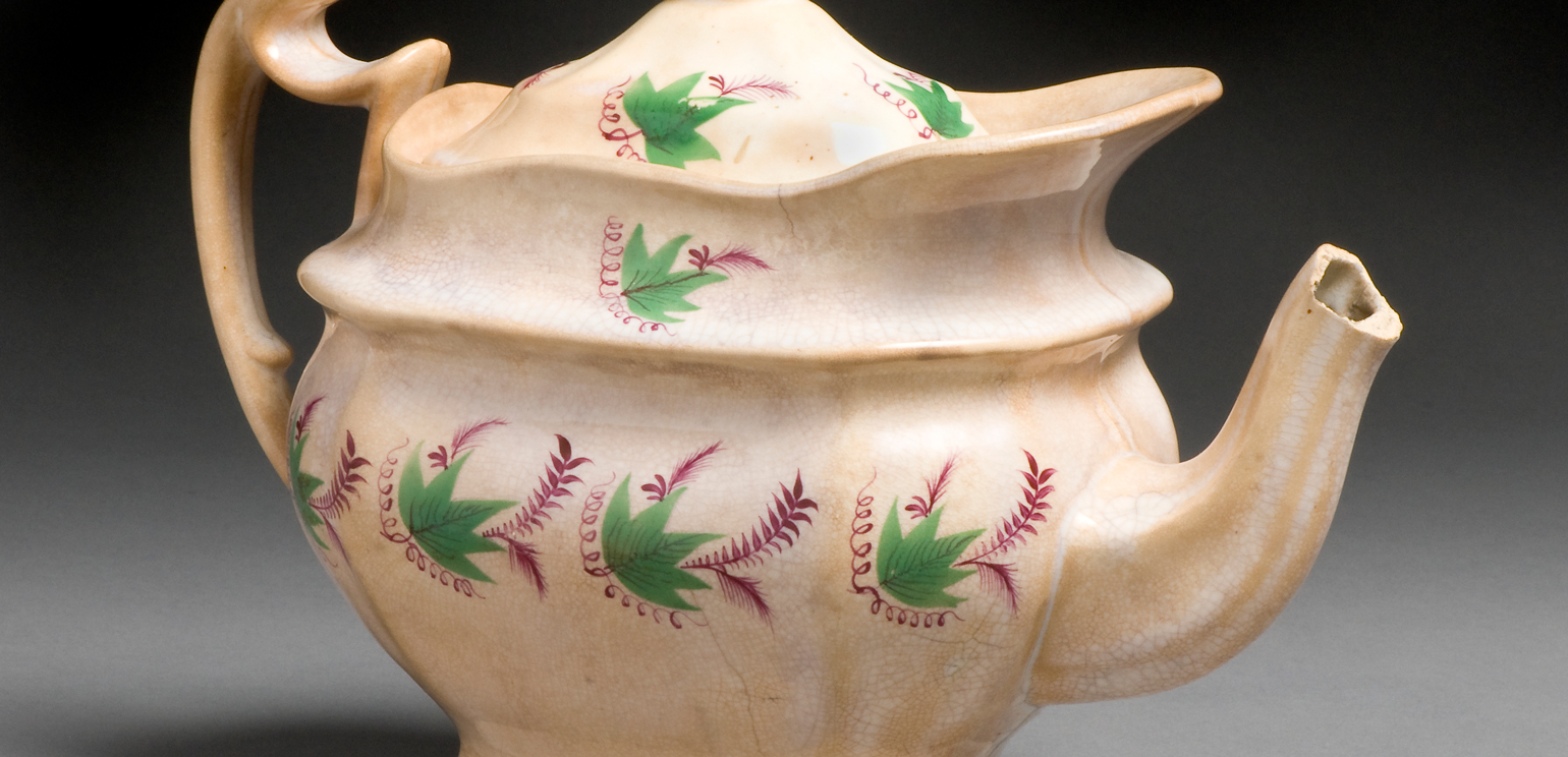 A Staffordshire teapot with an unusual, curvy, layered shape and little leaves and flowers painted on it in rows