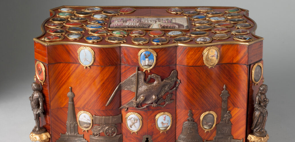 A color photograph of a presentation cigar box made of rosewood and decorated with many tiny hand-painted oval medallions that once belonged to a tsar of Russia