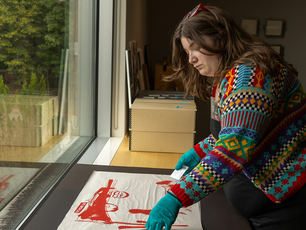 Mary Alice Smith, a curatorial intern, working with works on paper by a window