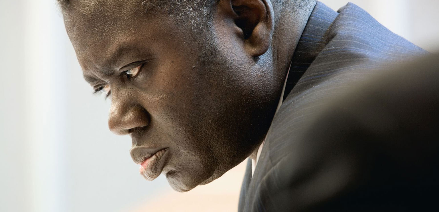 Detail of Joel Sternfeld's photograph "Latsoucabe Fall, Director of Planning and Equipment Senelec Energy, Senegal" from his series "When It Changed." It shows Fall in profile, looking seriously to the left.