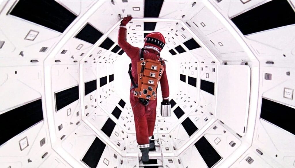 A still from "2001: A Space Odyssey" depicts a man in a red space suit in a futuristic spaceship