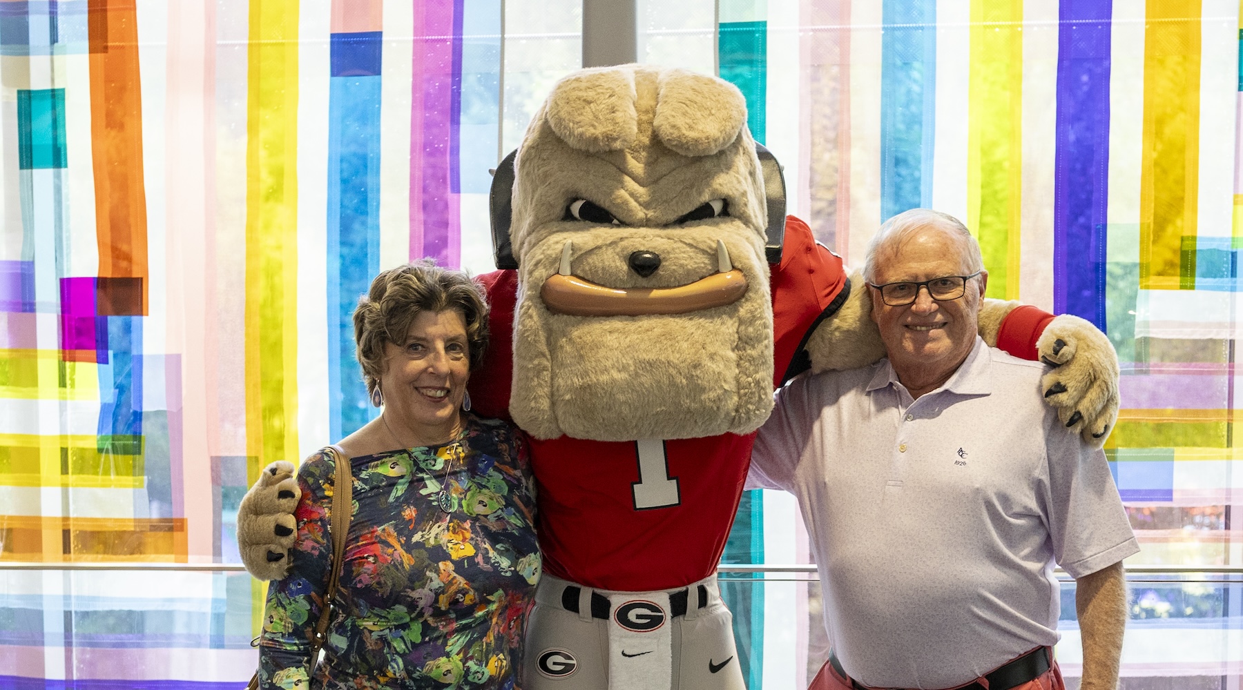 Museum docent Jean Petrovs (left) poses for a photo with UGA mascot Hairy Dawg and her husband