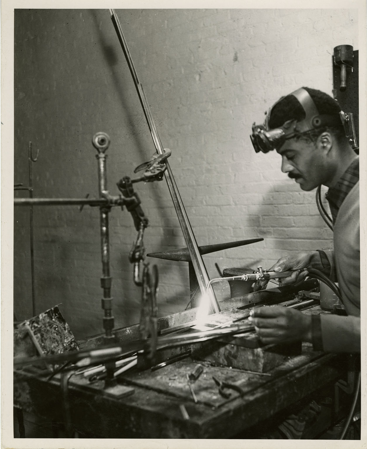 Black and white photograph of John Rhoden working on a sculpture with a welding torch. (John Rhoden Digital Archives/PAFA)