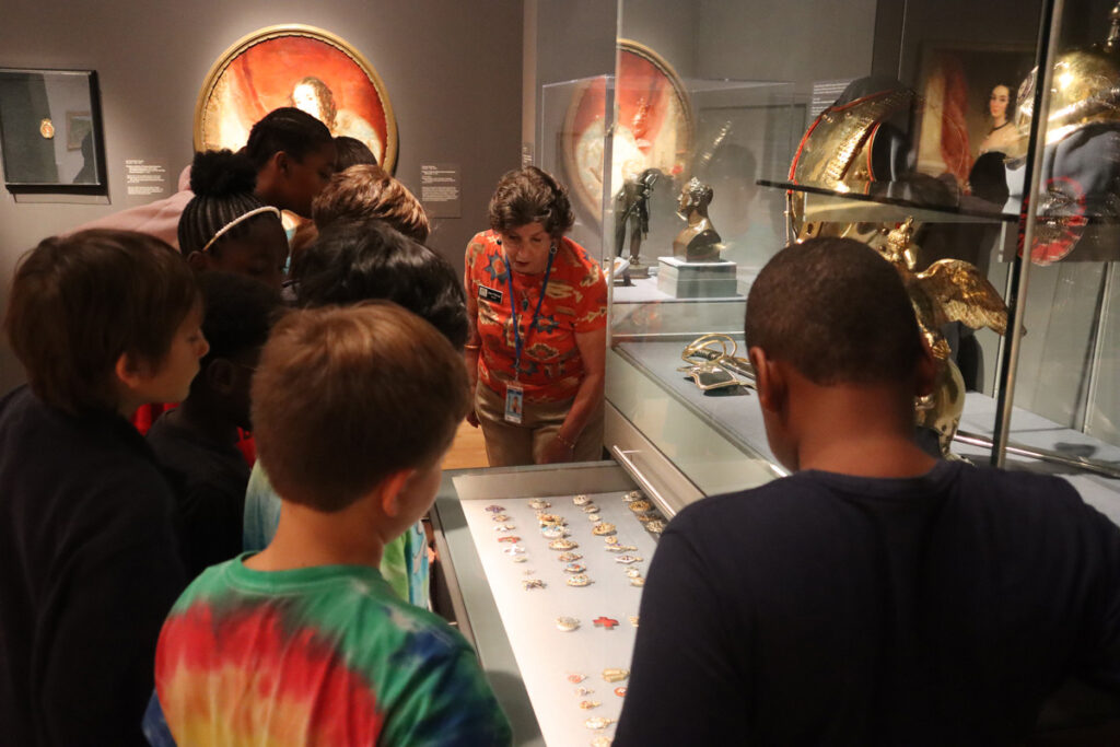 Docent Jean Petrovs shows a tour group a drawer full of Russian medals