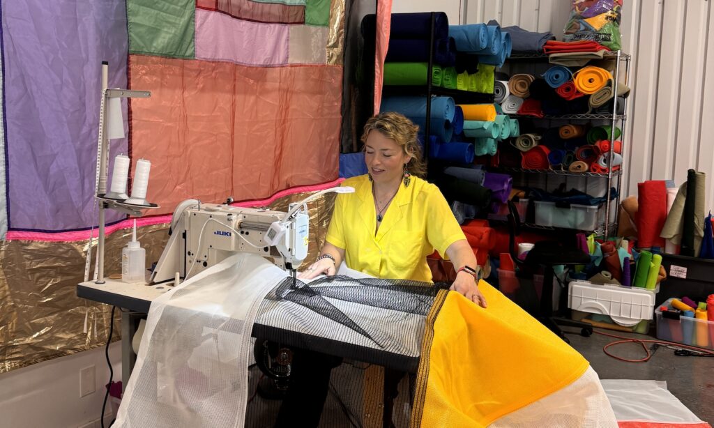A woman sitting at a sewing machine in a textile studio