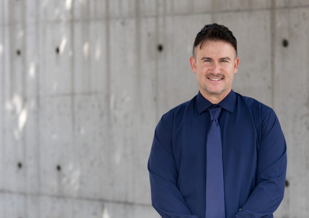 Kyle Gallagher standing in front of a concrete wall.