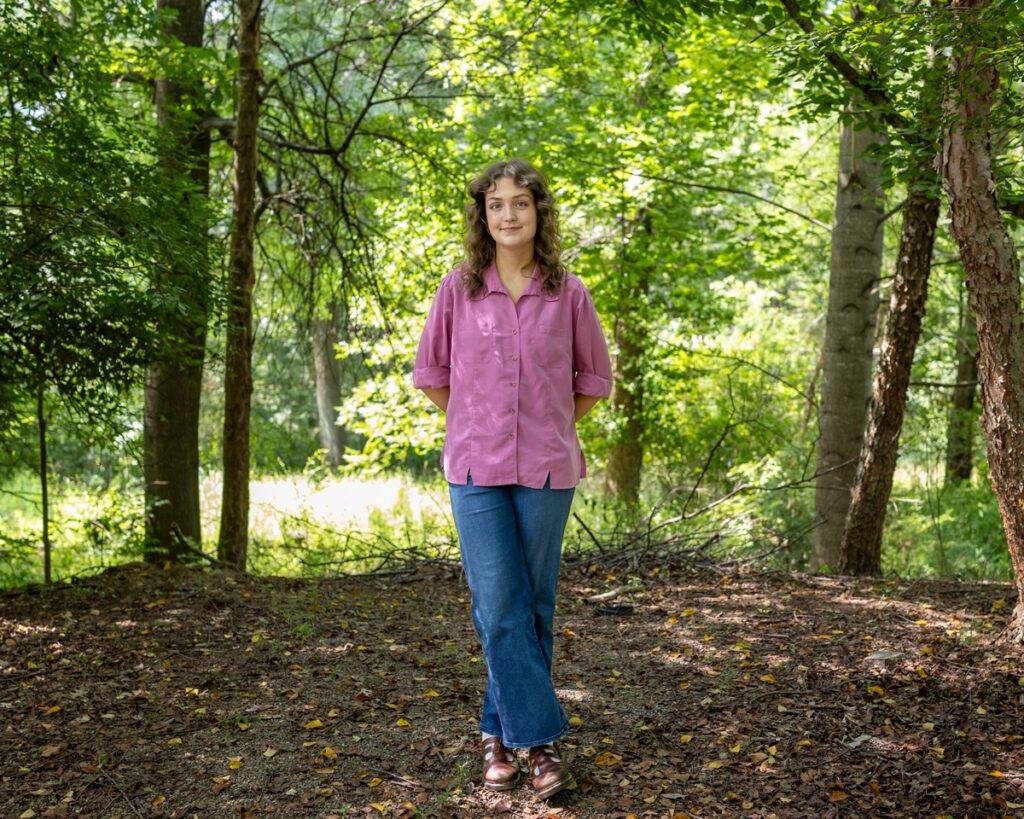 Caroline Moore, art handler, stands in a shady wooded area.