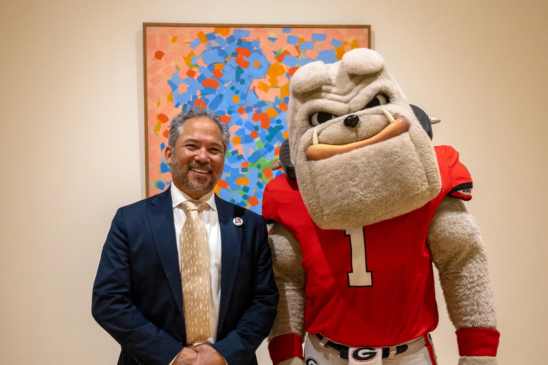 David Odo and Hairy Dawg, UGA's costumed bulldog mascot, stand together in front of "Two Women Bathing," an abstract painting by Carl Holty.