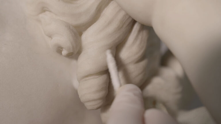 Amy Abbe cleans Edmonia Lewis’ “Cupid Caught” with a cotton swab