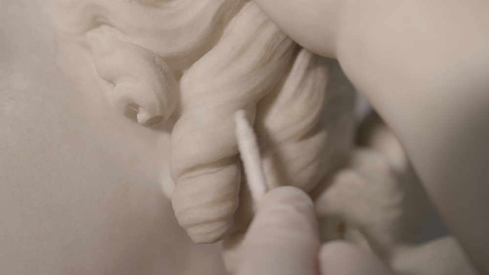 Amy Abbe cleans Edmonia Lewis’ “Cupid Caught” with a cotton swab