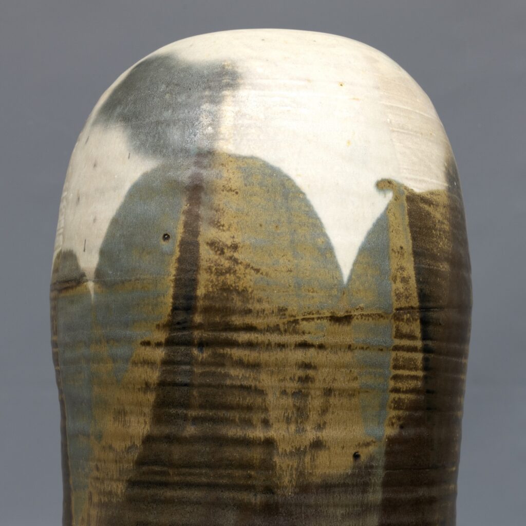 A detail shot of Toshiko Takaezu's ceramic work shows the rounded top with cream, brown, tan and bluish gray glazes.