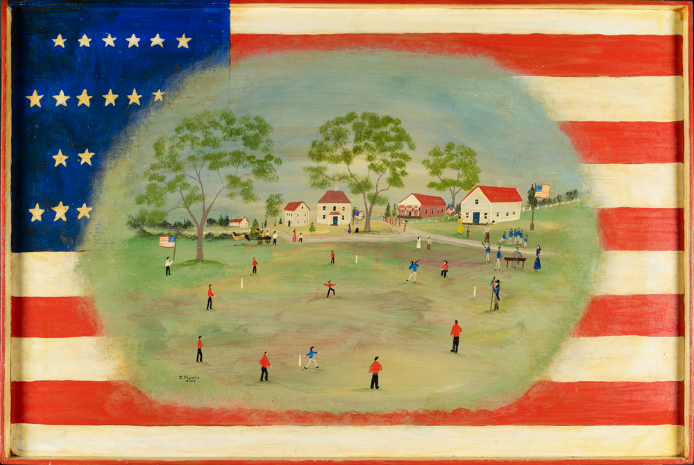 Charles Munro’s painting on wood features a painted American flag as a backdrop and a folk painting of a game of baseball superimposed on top of the flag in an oblong with soft edges. It’s an informal game on a regular field, with red-roofed white houses and trees in the background.